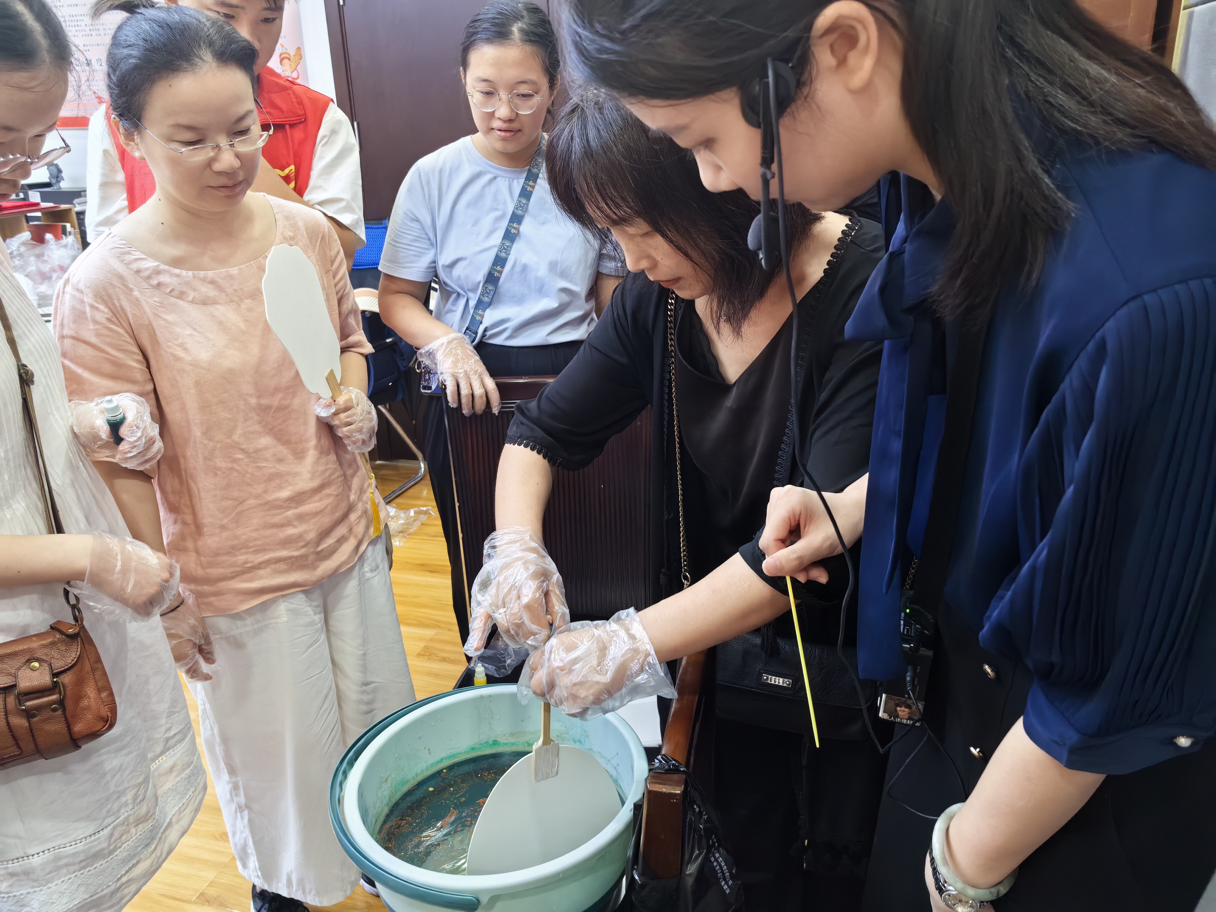 1723281947389396.jpg 讲解员与志愿者引导大家做漆扇1.jpg