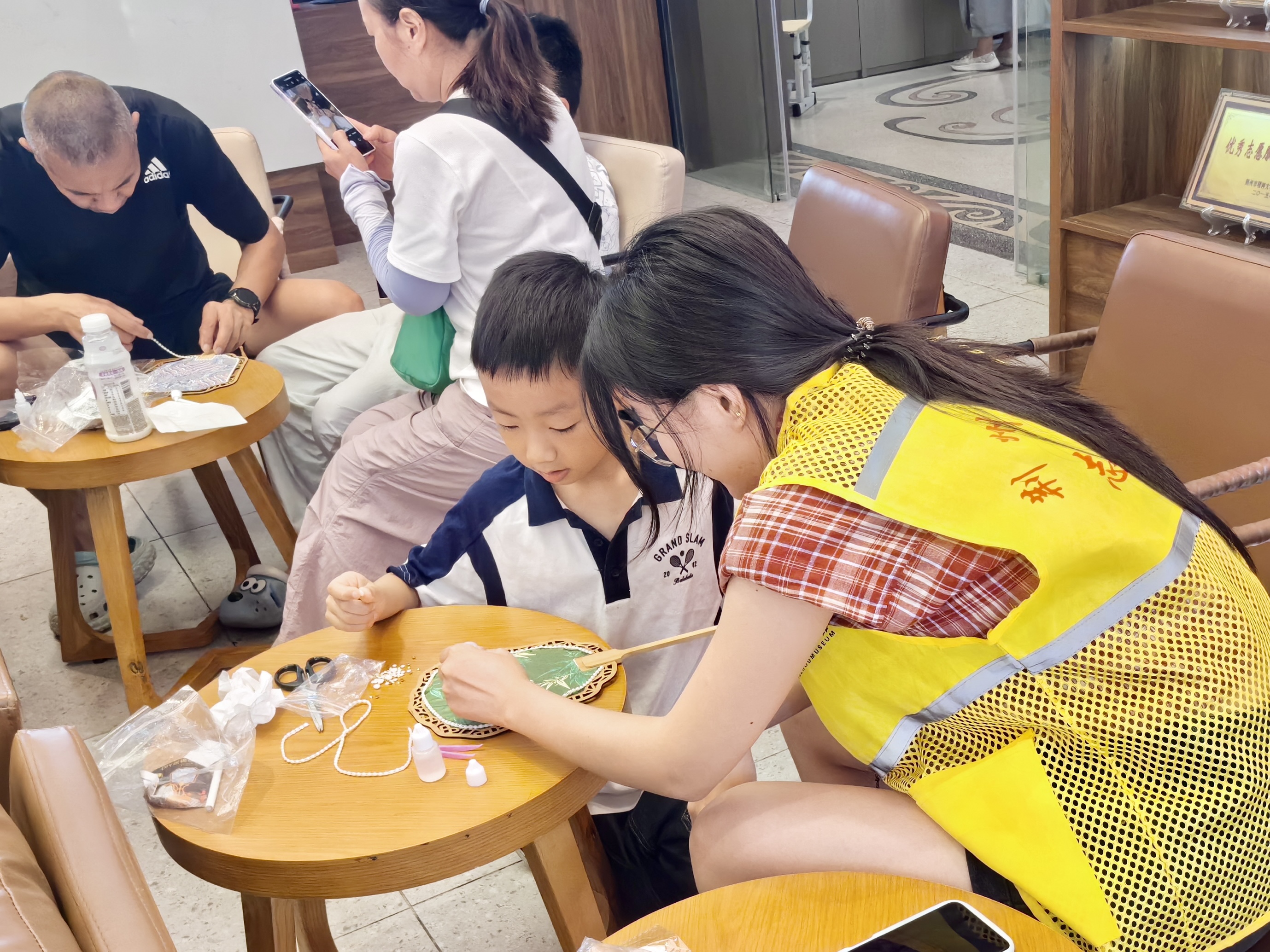 1756868874457787.jpg 3.志愿者帮助游客完成团扇.jpg